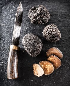 a knife and some kind of food on a black surface with it's contents cut in half