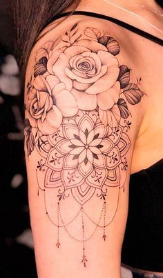 a woman's shoulder with a rose tattoo on her left arm and an intricate design