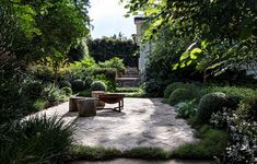 an outdoor patio area with stone pavers, trees and shrubbery on either side