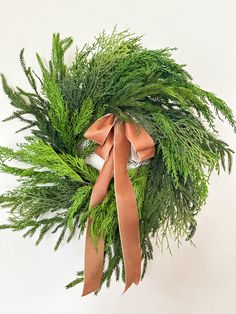 a green wreath with brown ribbon hanging on the wall