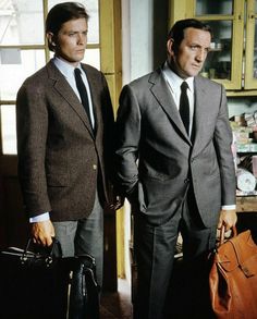 two men in suits and ties standing next to each other with luggage bags on the floor