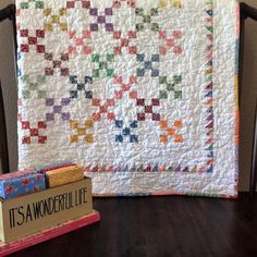 a book sitting on top of a wooden table next to a quilted wall hanging