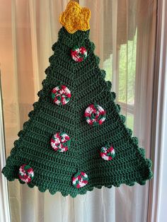 a crocheted christmas tree hanging on a window sill