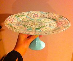 a person holding up a decorative plate with a blue cone in it's center