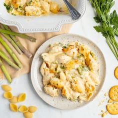 a white plate topped with macaroni and cheese next to asparagus