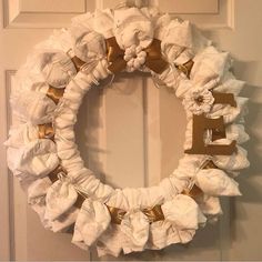 a white wreath with gold bows hanging on the front door