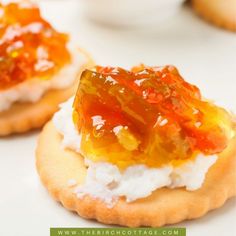 small crackers with jelly and cottage cheese on them sitting on a white table top