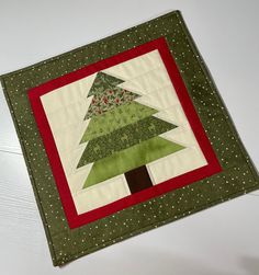 a green and red christmas tree quilted on top of a white table with polka dots