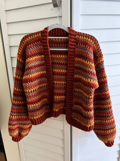 a crocheted jacket hanging on a white door