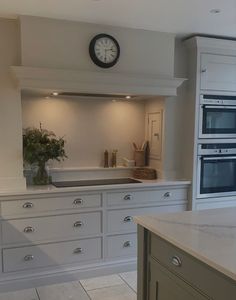 a kitchen with white cabinets and a clock on the wall above the stove top oven