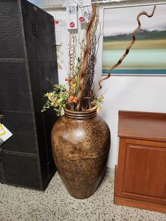 a large vase sitting on top of a floor next to a wooden cabinet and wall