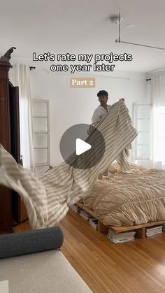 a man standing on top of a bed in a bedroom next to a wooden floor