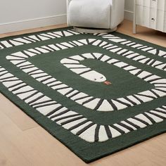 a green area rug with white and black designs on the floor next to a chair