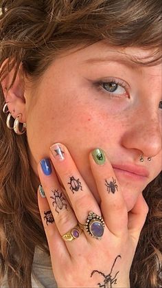 a woman with tattoos on her hands and fingers, holding her hand to her face