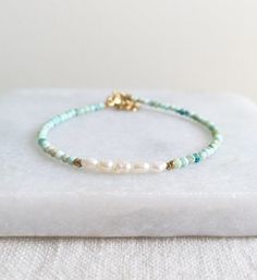 Beautiful Natural Turquoise beads and delicate Freshwater Pearls are used to create this modern boho beaded bracelet. D E T A I L S - Made with high quality Turquoise and Freshwater Pearl beads. - Five delicate Freshwater Pearls are centered among stunning natural Turquoise beads. - Non-tarnish 14k Gold-Filled chain adjuster. Gold-filled is a wonderful alternative to solid gold, and unlike gold plating, it is made to last a lifetime. - Lobster clasp closure. - Comes with a 1 inch adjuster. S I Z Turquoise And Pearl Bracelets, Bohemian Turquoise Friendship Bracelets With Spacer Beads, Bohemian Turquoise Pearl Bracelet With Round Beads, Elegant Turquoise Bracelets For Beach, Bohemian Turquoise Pearl Bracelet For Gift, Elegant Beach Beaded Bracelets With Gemstone Beads, Bohemian Turquoise Friendship Bracelets With Round Beads, Turquoise Bohemian Friendship Bracelets With Round Beads, Handmade Turquoise Amazonite Bracelets