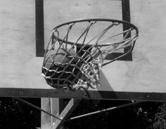 a basketball going through the hoop in black and white photo, taken from below it