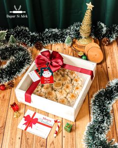 a white box filled with christmas treats on top of a wooden floor next to trees