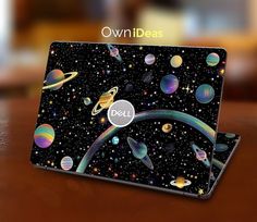 an open laptop computer sitting on top of a wooden table covered in planets and stars