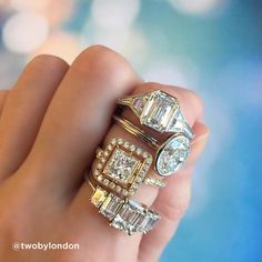 a woman's hand holding three rings with diamonds on top and two smaller ones in the middle