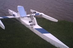 a white and blue boat sitting on top of grass next to the water's edge