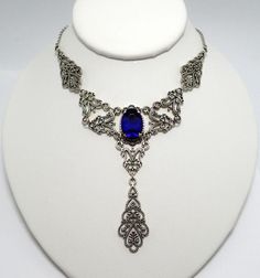 This is a new handmade necklace. It is made with antiqued silver plated filigrees, accented with a high quality DARK COBALT BLUE glass rhinestone. Decorated portion is 6" wide and 3 1/4" tall in the center. Necklace is adjustable 15-18" with a lobster clasp and chain extender. If you would like a different length, please send us a message. Gothic Filigree Necklace For Wedding, Gothic Wedding Necklace With Filigree Detail, Gothic Filigree Wedding Necklace, Gothic Metal Jewelry With Filigree, Gothic Antique Silver Jewelry With Intricate Design, Gothic Filigree Metal Jewelry, Antique Silver Gothic Filigree Jewelry, Antique Silver Gothic Jewelry With Filigree, Gothic Antique Silver Filigree Jewelry