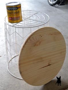 a wooden object sitting on the ground next to a wire rack with paint in it