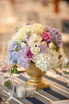 a vase filled with lots of purple and white flowers sitting on top of a table