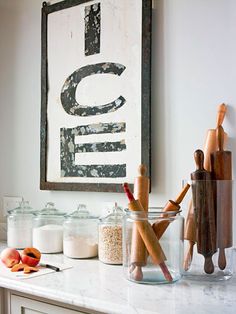 a kitchen counter with jars and utensils on it in front of a framed sign