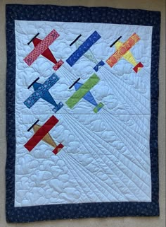 a quilted wall hanging with small airplanes on it