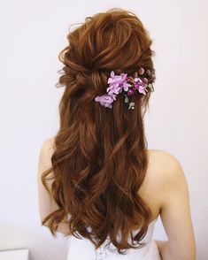 a woman with long brown hair and flowers in her hair is shown from the back