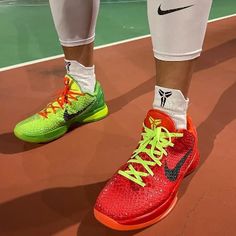 the legs and feet of a tennis player wearing red, yellow and green shoes on a court