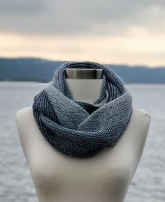 a white mannequin wearing a blue knitted scarf on top of a body of water