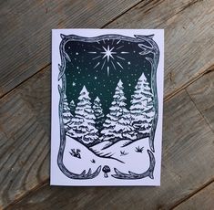 a card with trees and stars in the night sky on a wooden table next to wood planks