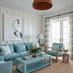 a living room with blue couches and chairs in front of a painting on the wall