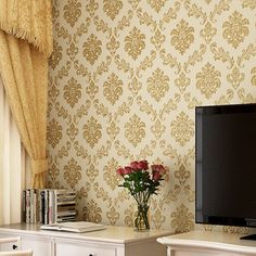 a tv sitting on top of a white dresser next to a vase filled with flowers