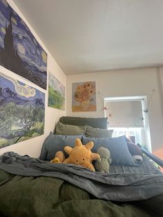 there is a stuffed animal that is on the bed in front of two paintings hanging on the wall