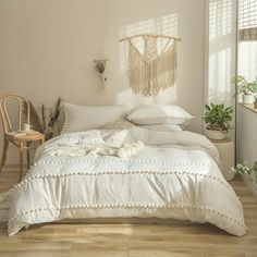 a white bed sitting in a bedroom next to a wooden table and chair on top of a hard wood floor