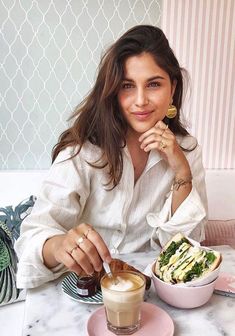 a woman sitting at a table with food and drink