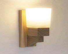 a wooden light fixture mounted to the side of a wall next to a white wall