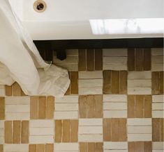 a bath tub sitting under a window next to a white towel on top of a tiled floor