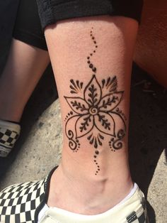 a woman's foot with a black and white tattoo design on the side of her leg