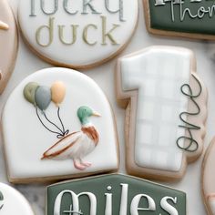 decorated cookies with the number one and balloons are displayed on a white tablecloth that says 1, lucky duck