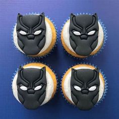 four decorated cupcakes with black panther face on top and white frosting around the edges