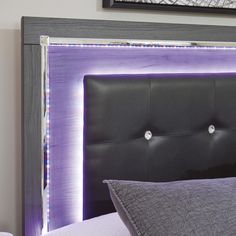 the headboard of a bed with purple lights on it