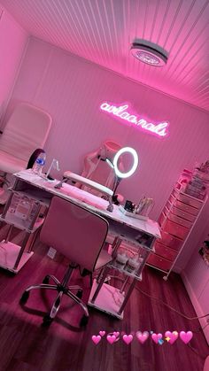 a pink room with a desk, chair and neon sign on the wall above it