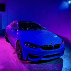 a blue car parked in a garage with purple lighting