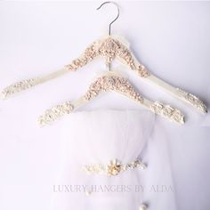 a wedding dress hanging on a hanger with pearls and laces attached to it