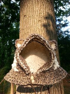 a crocheted hat hanging from the side of a tree