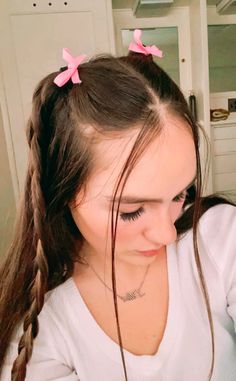 a girl with two pink bows in her hair is looking down at something on the table