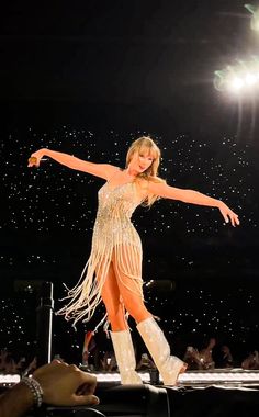 a woman in a fringed dress on stage with her arms out and legs spread wide